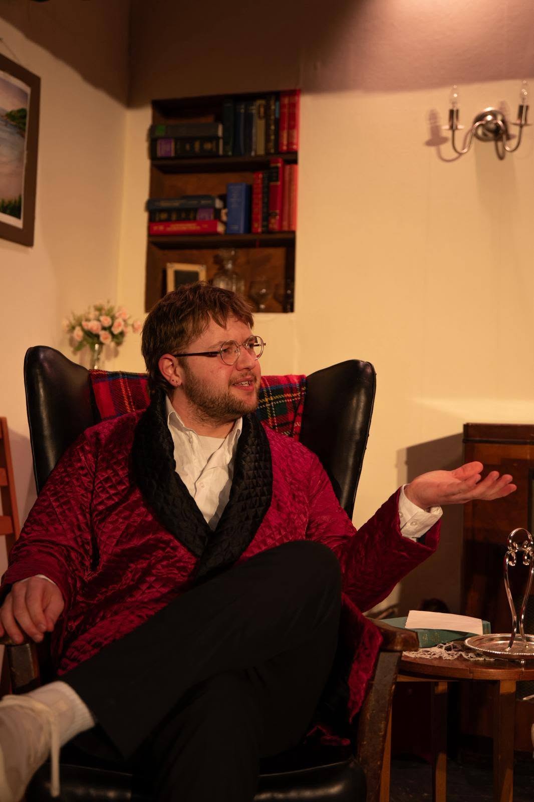 Connor Michie as Charles Condomine seated in the Condomines’ living room