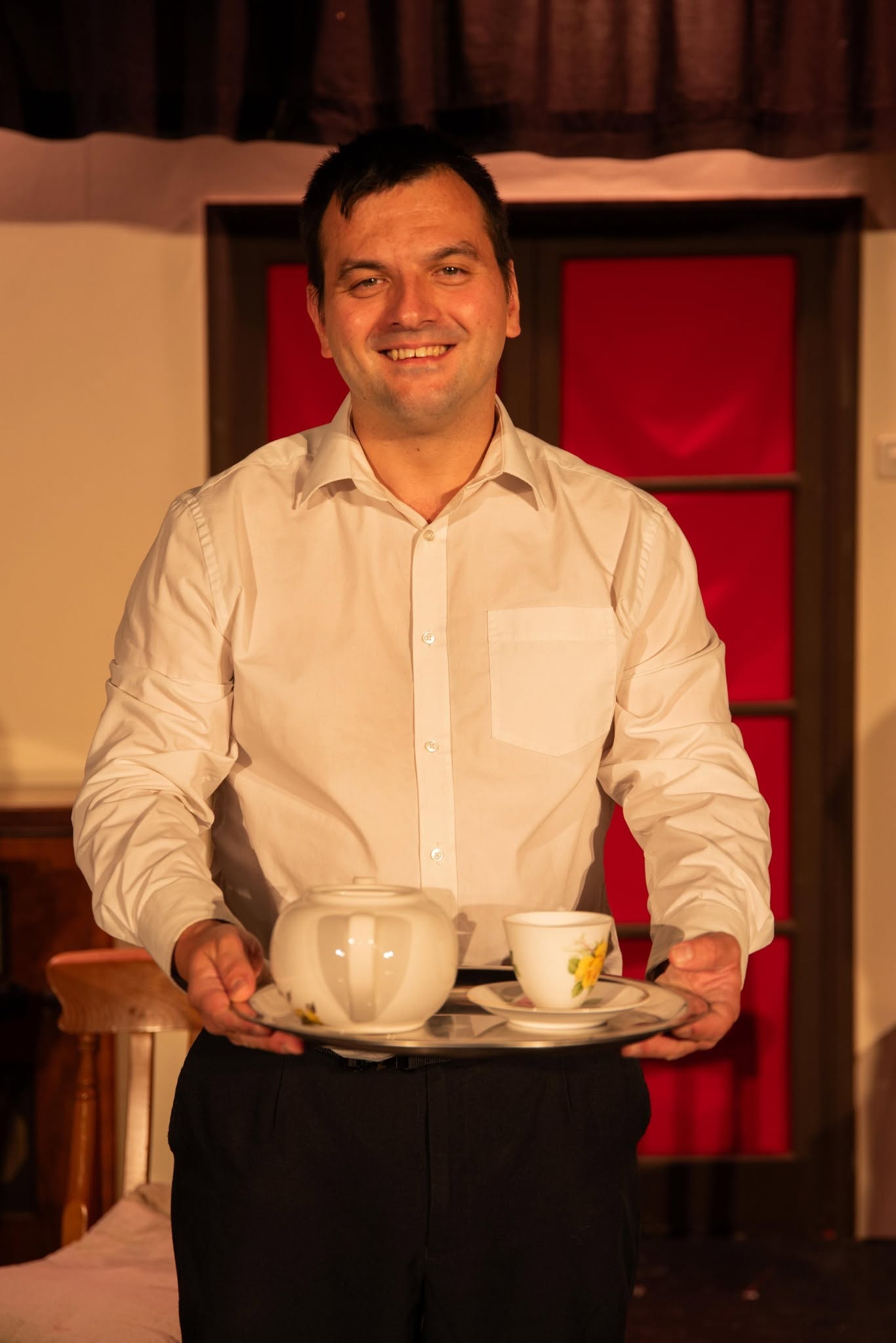 A Blithe Spirit cast member carrying a tea tray on stage